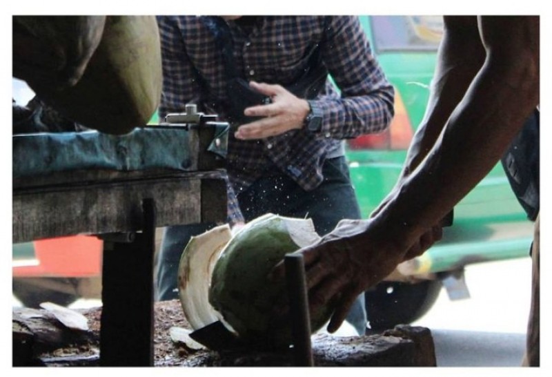 Seorang sedang memotong kelapa muda